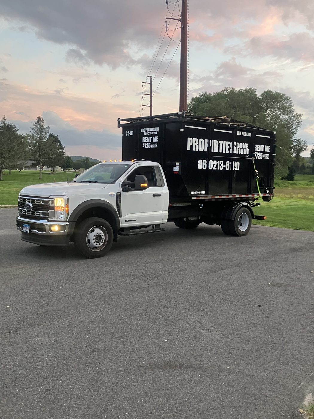 Properties Done Right dumpster truck with a branded roll off container
